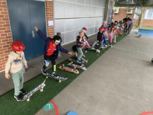Kids learning to skateboard in a line.