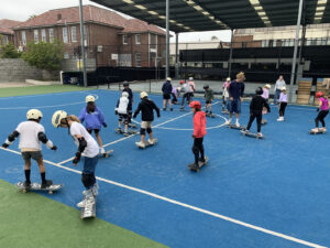 Kids learning to ride skateboards at vacation care.