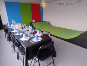 Skateboarding birthday party table set up with skate ramp in the background.