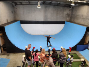 Demo to kids learning to skate with a vert ramp in the background at a skateboarding birthday party.